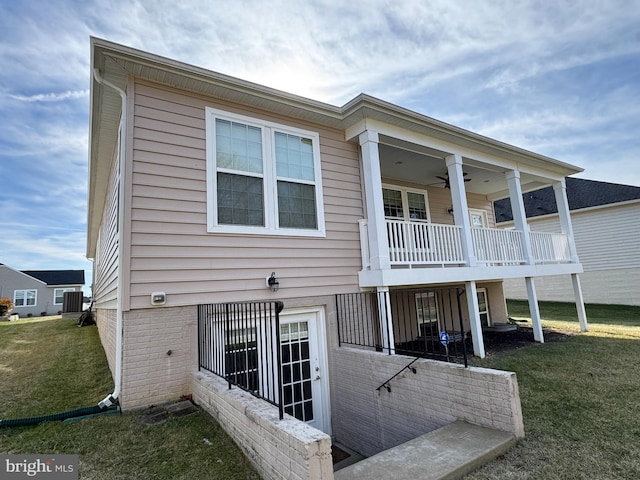 back of property featuring a lawn, a balcony, ceiling fan, and central air condition unit