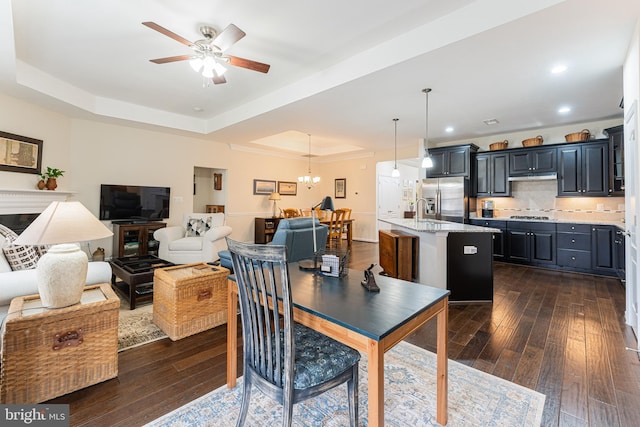 dining area with a raised ceiling, sink, dark hardwood / wood-style floors, and ceiling fan with notable chandelier