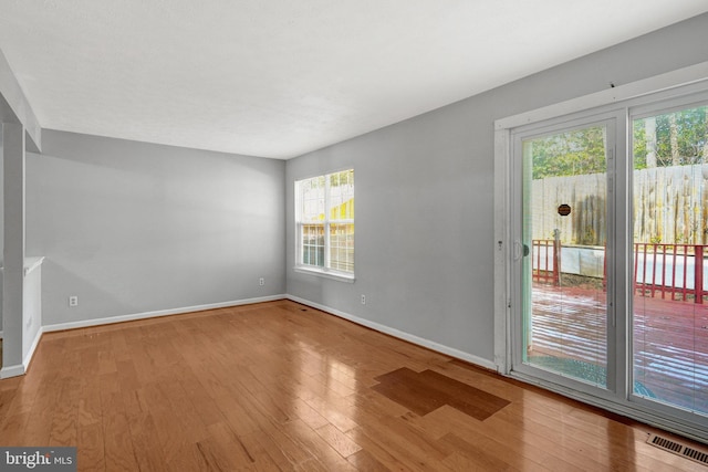 empty room with visible vents, baseboards, and wood finished floors