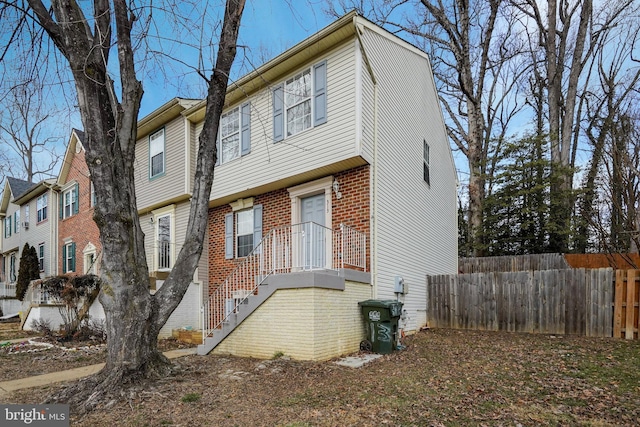 view of property exterior with stairs, fence, and brick siding