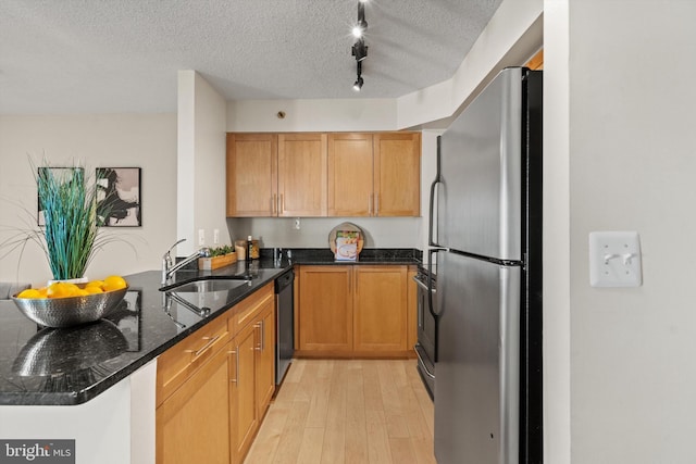 kitchen with sink, appliances with stainless steel finishes, dark stone countertops, a textured ceiling, and kitchen peninsula