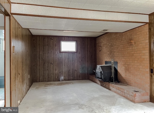 basement featuring wooden walls and a wood stove