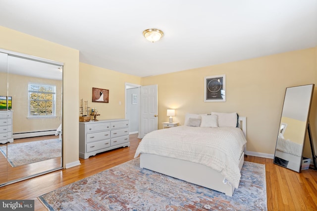 bedroom with a baseboard heating unit and light hardwood / wood-style flooring