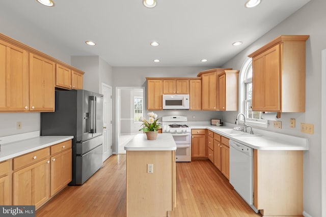 kitchen with white appliances, recessed lighting, a sink, and a center island