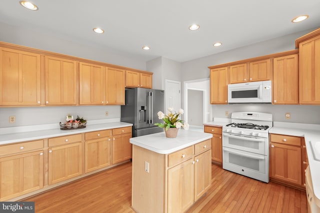 kitchen featuring recessed lighting, light countertops, light wood-style floors, a kitchen island, and white appliances