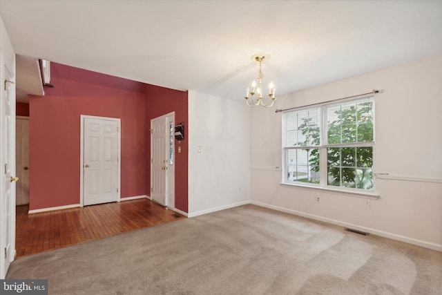 empty room with carpet flooring and an inviting chandelier