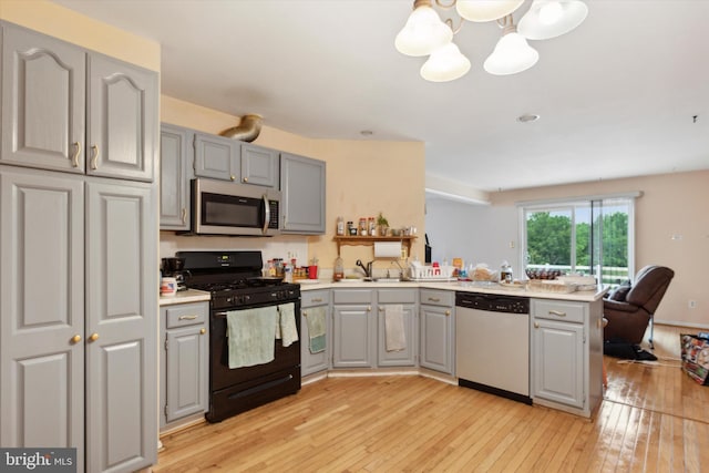 kitchen with appliances with stainless steel finishes, gray cabinetry, kitchen peninsula, and light hardwood / wood-style flooring