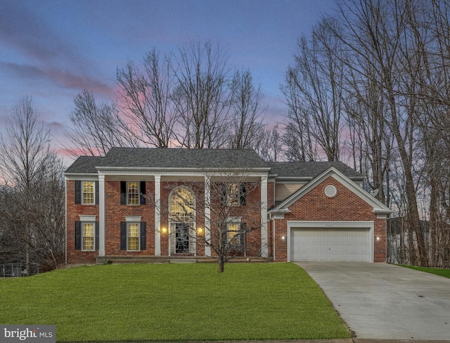 neoclassical home featuring driveway, a front lawn, a shingled roof, and brick siding