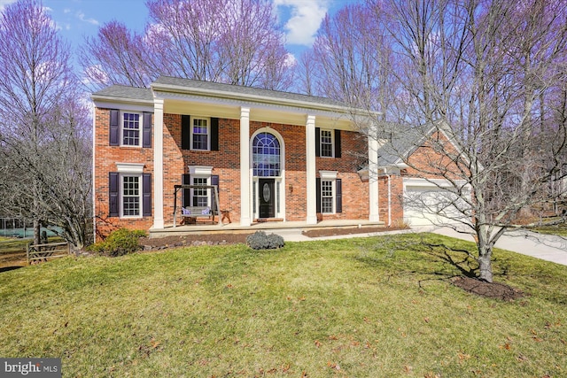 greek revival house with brick siding, a garage, driveway, and a front lawn