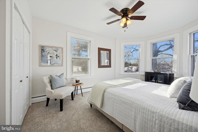 bedroom featuring a baseboard heating unit, light carpet, ceiling fan, and a closet