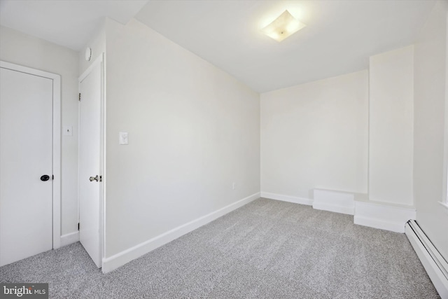 carpeted spare room with a baseboard heating unit