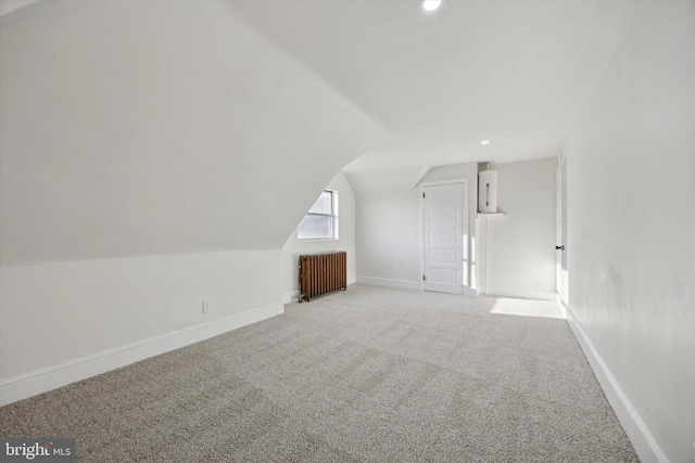 additional living space featuring carpet floors, vaulted ceiling, and radiator