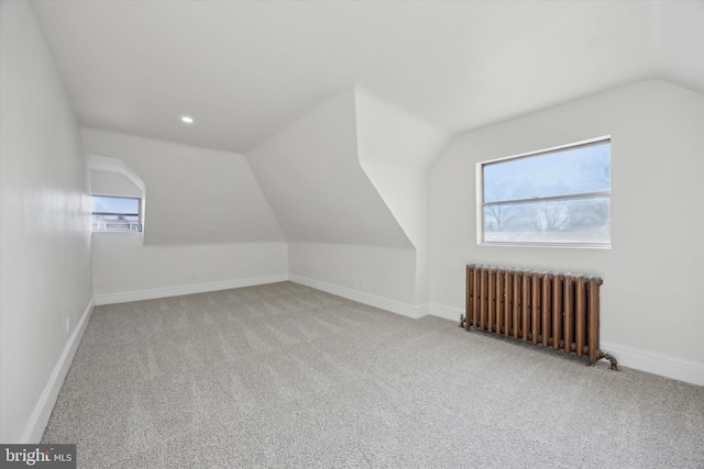 bonus room featuring lofted ceiling, radiator heating unit, and light colored carpet