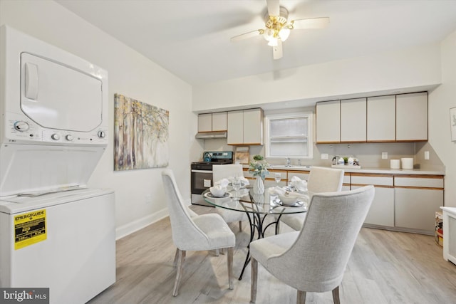 dining space with stacked washer / dryer, ceiling fan, sink, and light wood-type flooring