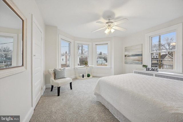 carpeted bedroom with multiple windows, radiator heating unit, and ceiling fan