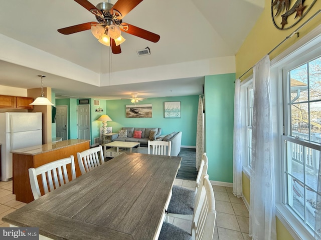 dining area featuring light tile patterned floors, a tray ceiling, and ceiling fan