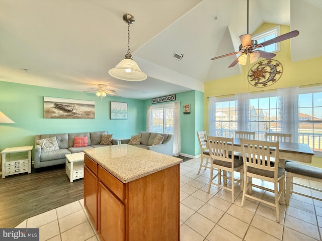 kitchen featuring light tile patterned floors, ceiling fan, high vaulted ceiling, light stone counters, and decorative light fixtures