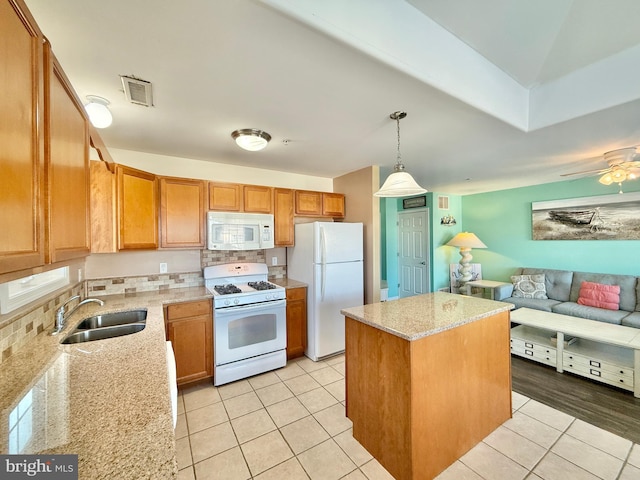 kitchen with decorative light fixtures, sink, a center island, light stone counters, and white appliances