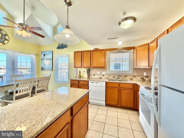 kitchen with sink, white appliances, light stone counters, light tile patterned flooring, and decorative light fixtures