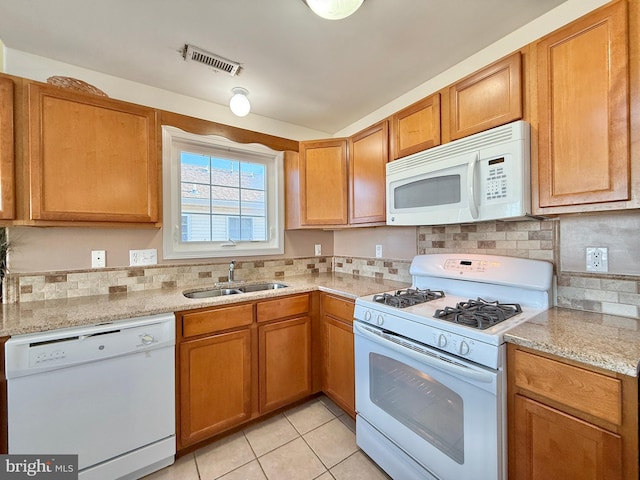 kitchen with light stone countertops, sink, backsplash, and white appliances