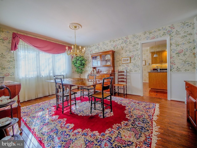 dining area with sink, wood-type flooring, and a chandelier