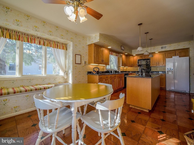 dining area featuring ceiling fan, dark parquet flooring, and sink