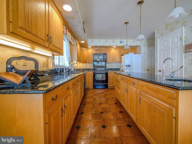 kitchen featuring decorative light fixtures, a kitchen island with sink, sink, and black appliances