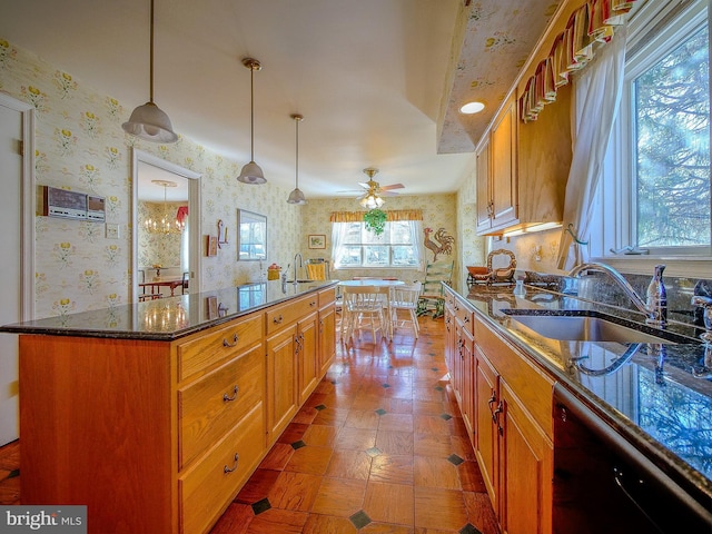 kitchen featuring pendant lighting, sink, dishwasher, a kitchen island, and dark stone counters