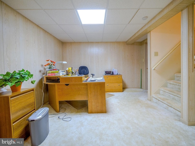 office area with a paneled ceiling and wood walls