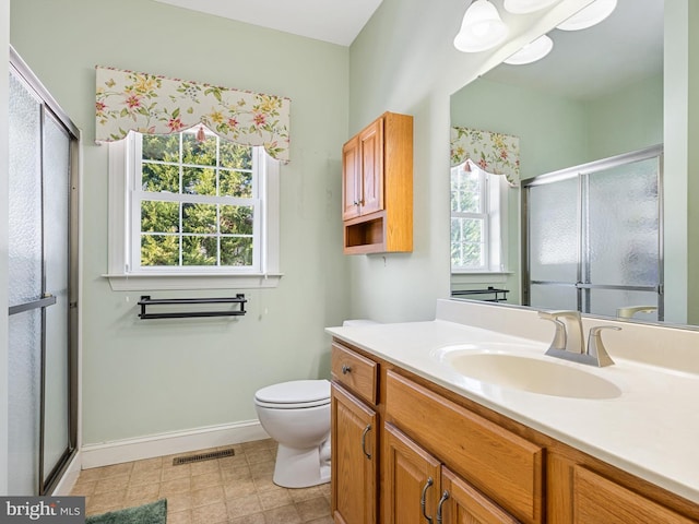 bathroom featuring vanity, a shower with door, and toilet