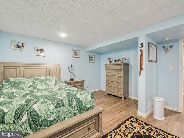 bedroom featuring a drop ceiling and light wood-type flooring