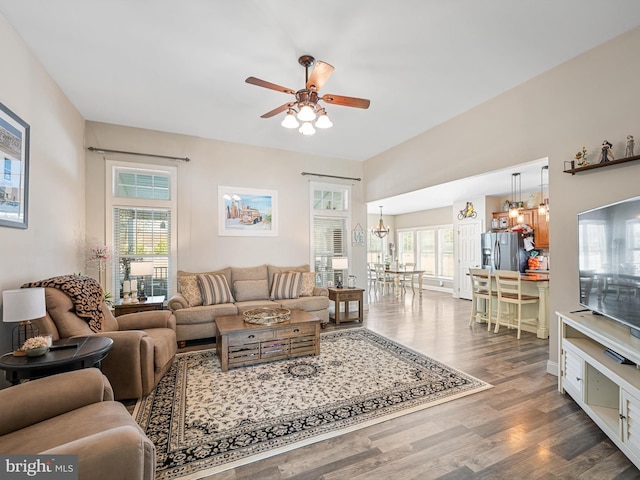 living room featuring ceiling fan with notable chandelier and dark hardwood / wood-style flooring