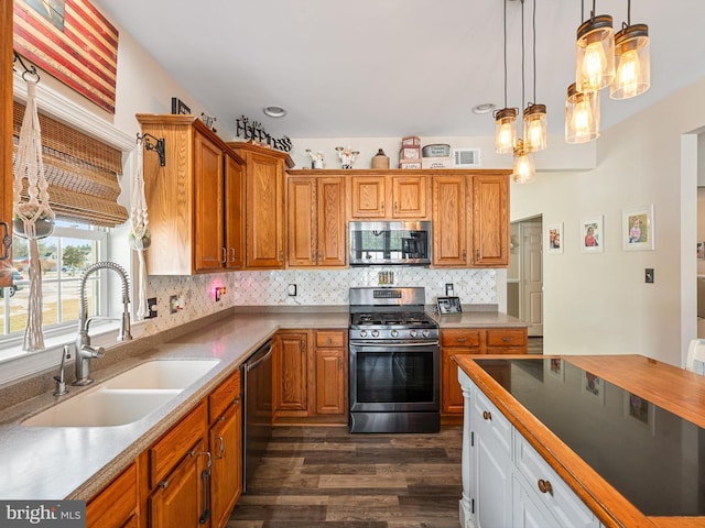 kitchen featuring dark hardwood / wood-style floors, pendant lighting, tasteful backsplash, sink, and stainless steel appliances