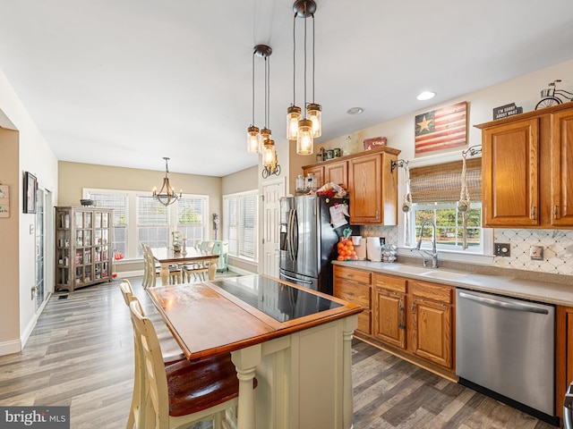 kitchen with decorative light fixtures, stainless steel appliances, hardwood / wood-style flooring, and a kitchen island