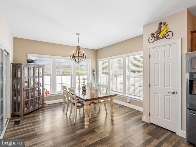 dining space with dark wood-type flooring and an inviting chandelier