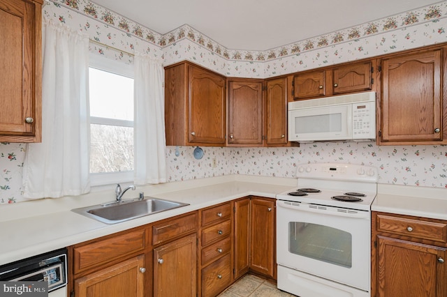 kitchen with a sink, white appliances, brown cabinets, and wallpapered walls