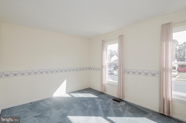 unfurnished room featuring carpet, visible vents, and baseboards