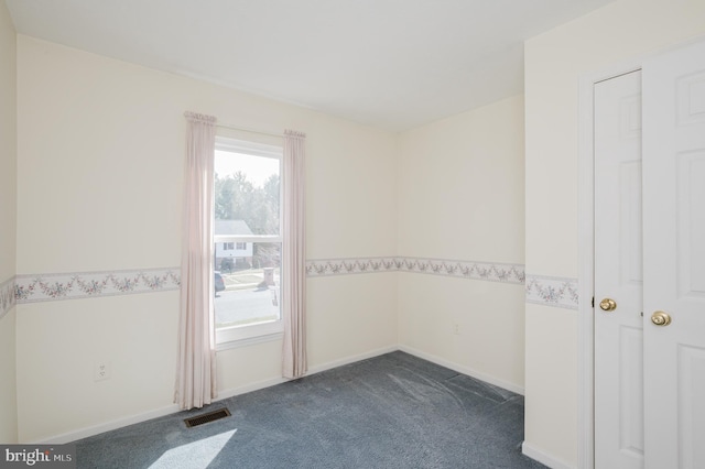 empty room featuring visible vents, baseboards, and dark colored carpet