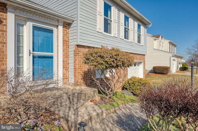 view of side of home featuring an attached garage and brick siding