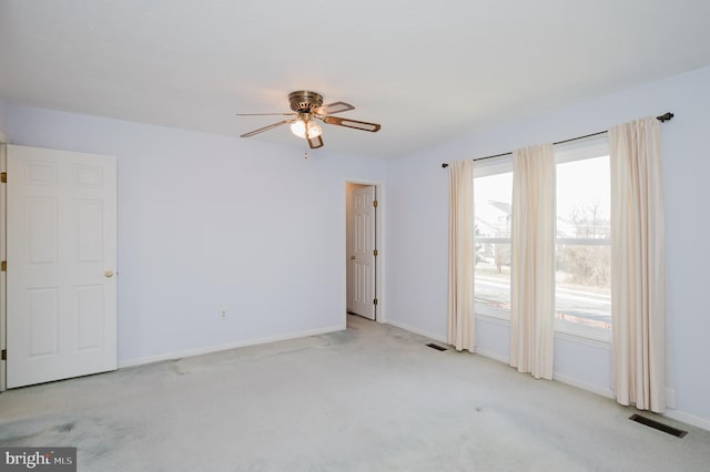 carpeted spare room with a ceiling fan, baseboards, and visible vents