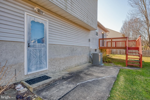 exterior space with stucco siding, a yard, central AC unit, and a wooden deck