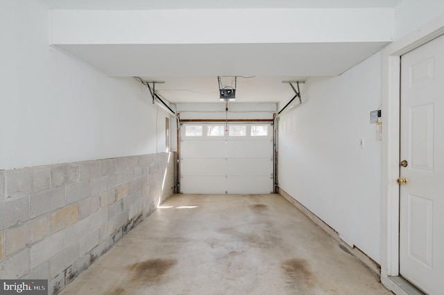 garage featuring concrete block wall and a garage door opener