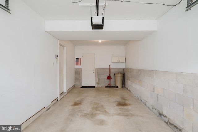 garage with concrete block wall and a garage door opener