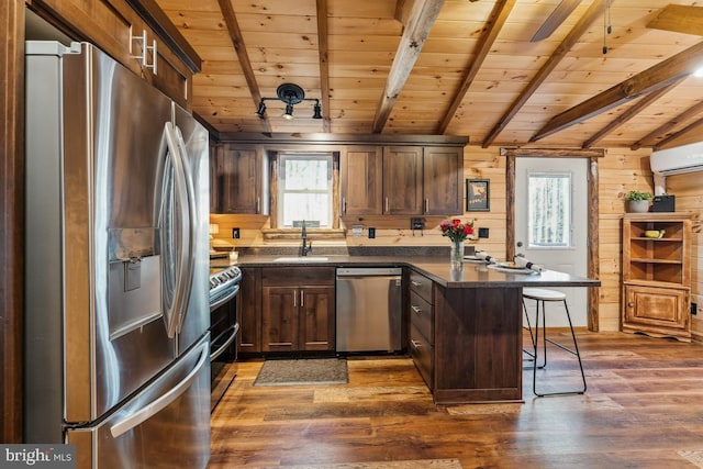 kitchen featuring appliances with stainless steel finishes, an AC wall unit, sink, a kitchen breakfast bar, and wood ceiling