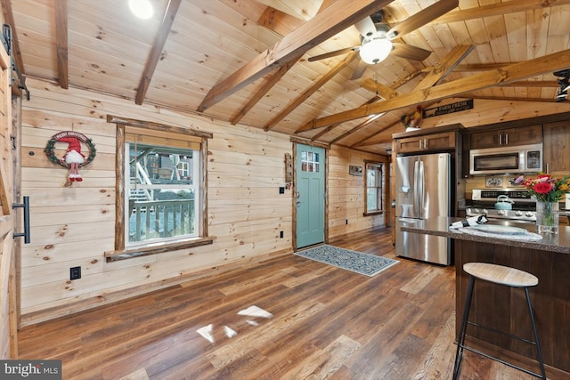 kitchen with vaulted ceiling with beams, dark brown cabinets, stainless steel appliances, wooden walls, and dark hardwood / wood-style flooring