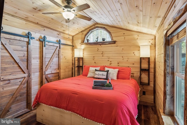 bedroom with vaulted ceiling, wood walls, hardwood / wood-style flooring, wood ceiling, and a barn door