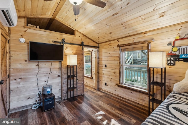 unfurnished bedroom featuring lofted ceiling, wood walls, a wall unit AC, hardwood / wood-style flooring, and a barn door