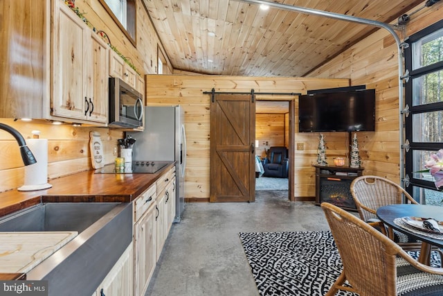 kitchen with butcher block counters, black electric cooktop, a barn door, and wood walls