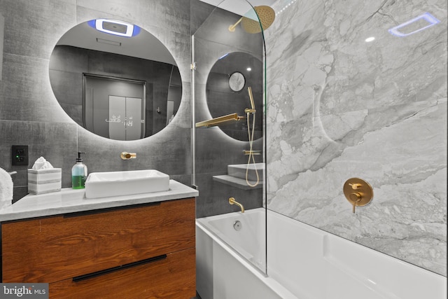 bathroom featuring tiled shower / bath, vanity, and tile walls