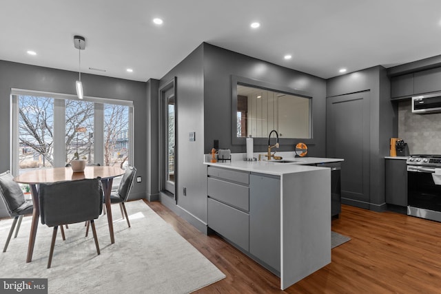 kitchen with dark wood-type flooring, sink, decorative light fixtures, gray cabinets, and stainless steel stove